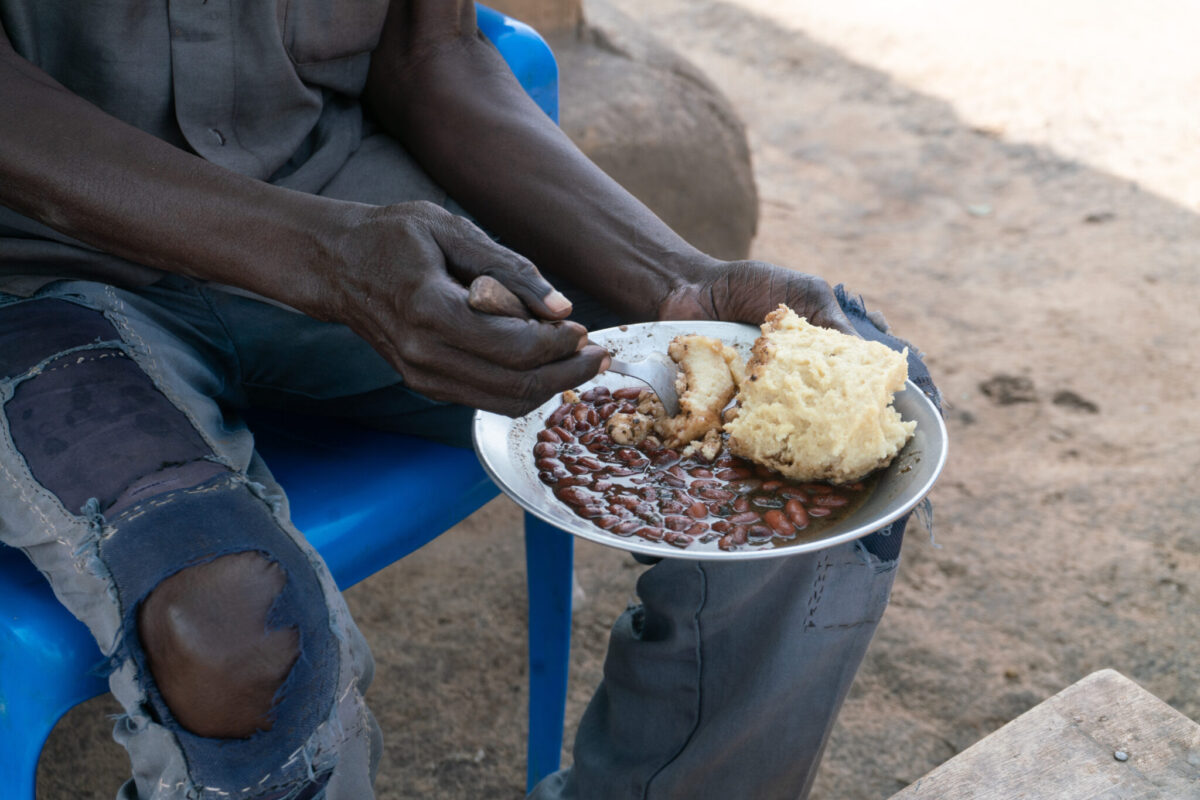 Hands holding a bowl of beans and maize porridge