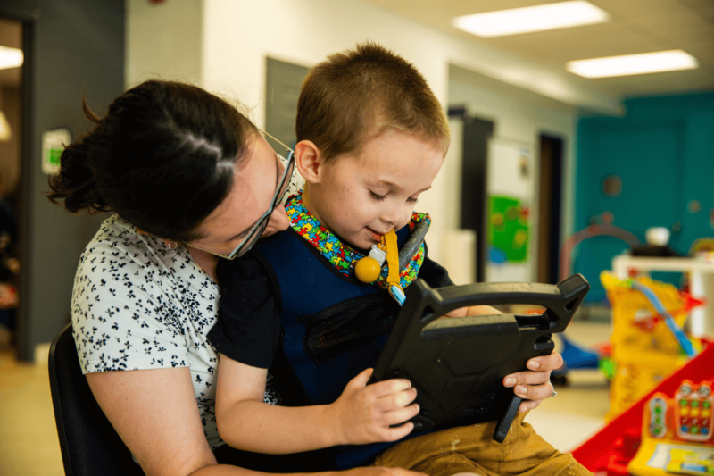 child holding pad while being comforted by counselor