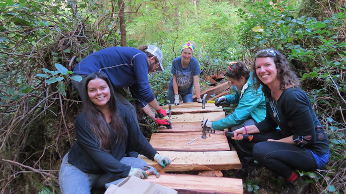 A few volunteers pose while nailing cedar planks into the boardwalk.