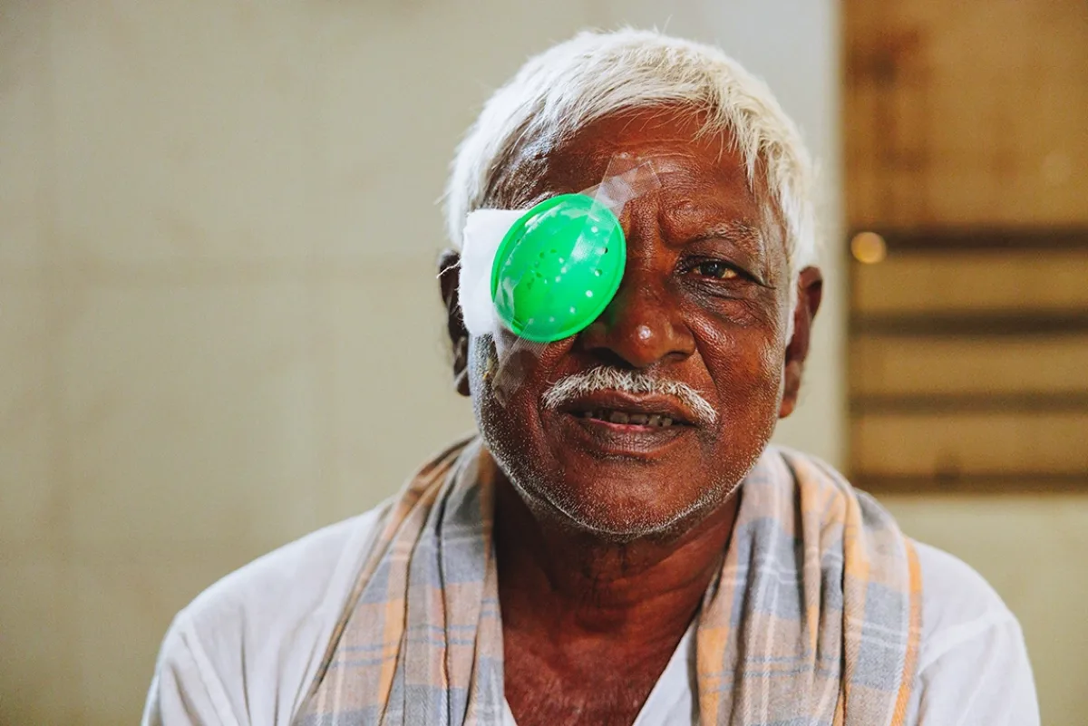A man wears a green eye patch while recovering from cataract surgery.