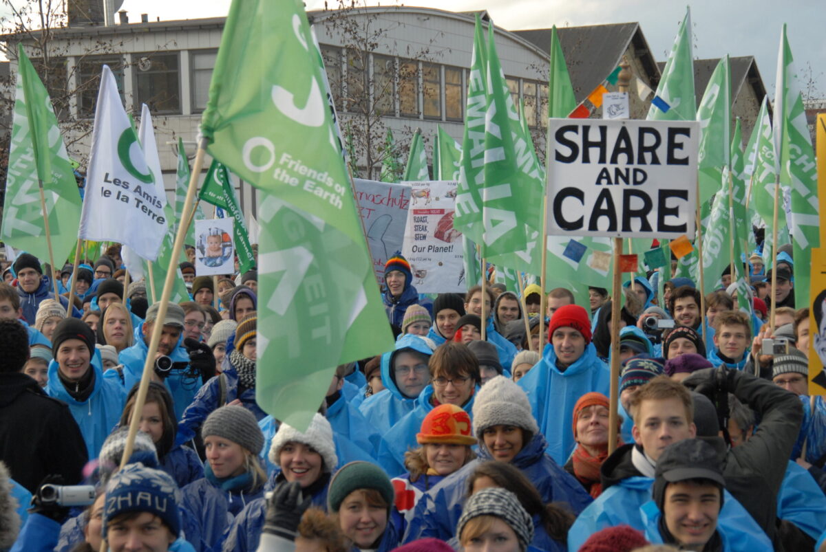 Flags and signs held by a large group of people.