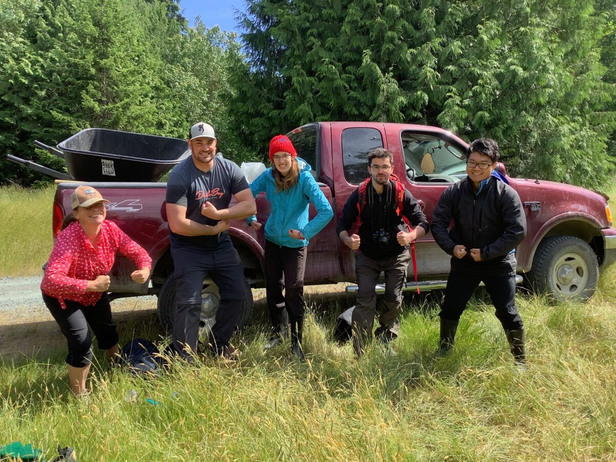 5 young people grinning, by a truck
