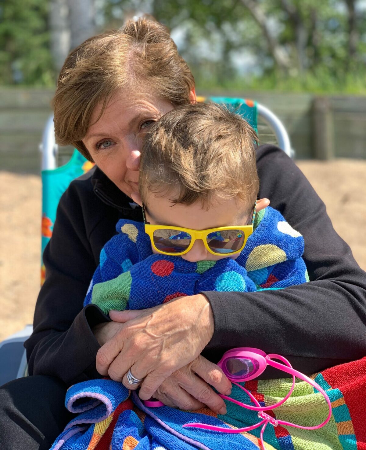 A grandma and grandson enjoy a snuggle on the beach at Waskesiu Lake