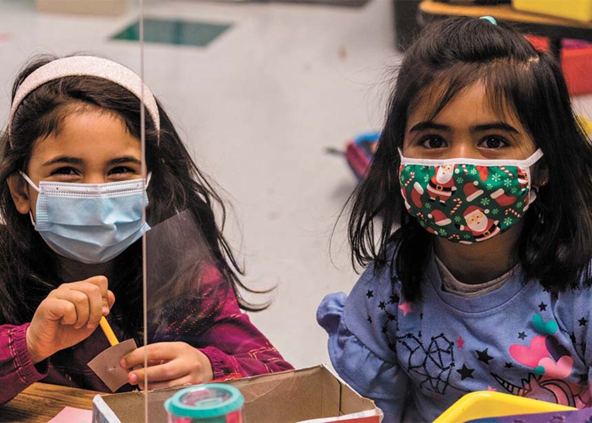 Two girls in masks, playing and smiling together