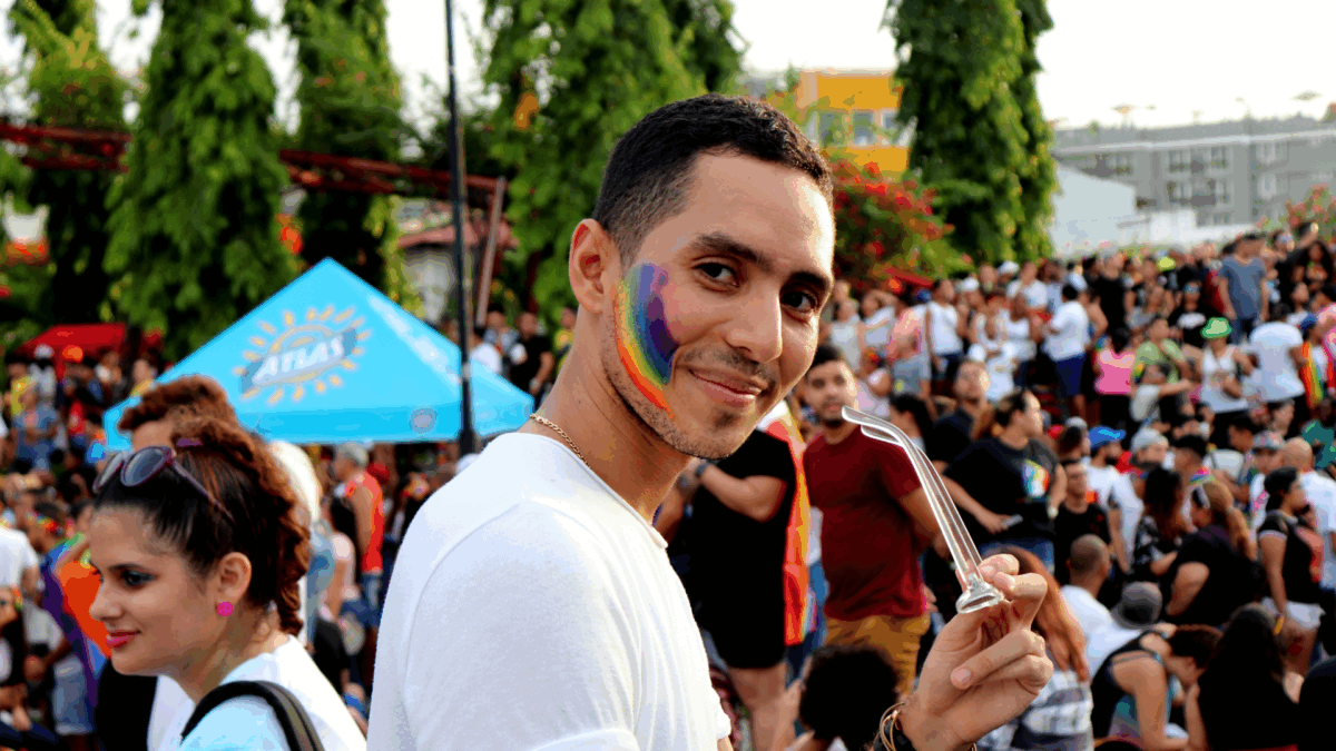 A person at a pride event with a rainbow on their cheek.