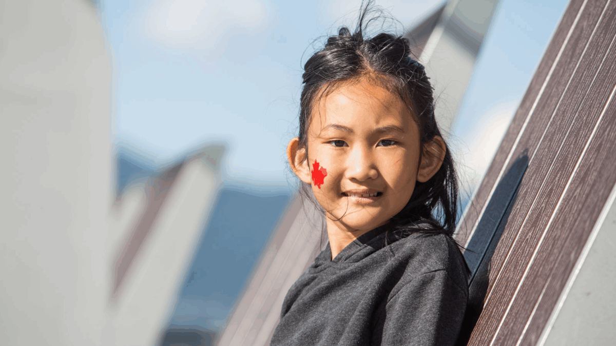 Little girl with maple leaf on her cheek.
