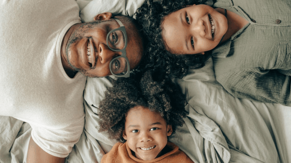 Dad lying with two children looking up.