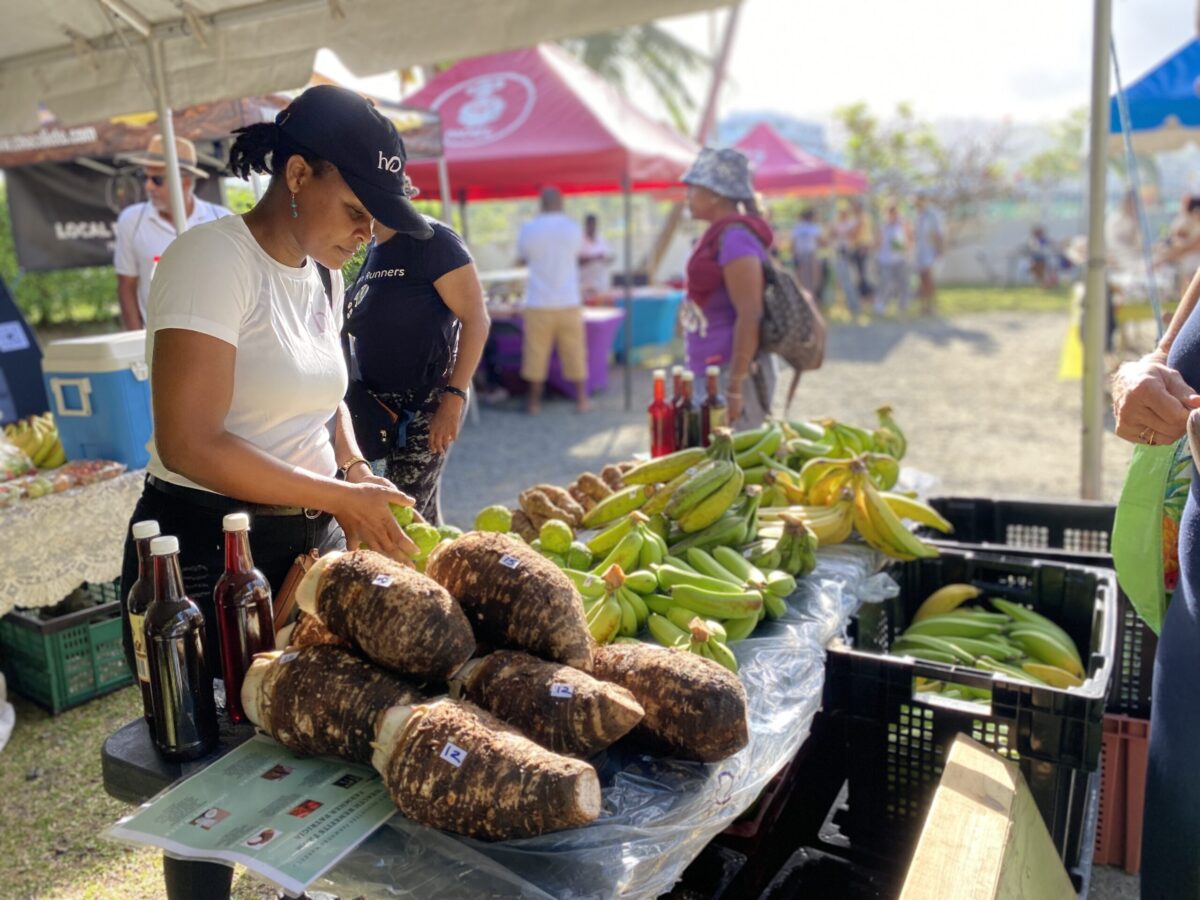 A woman is setting up a farmers market stall with bananas.