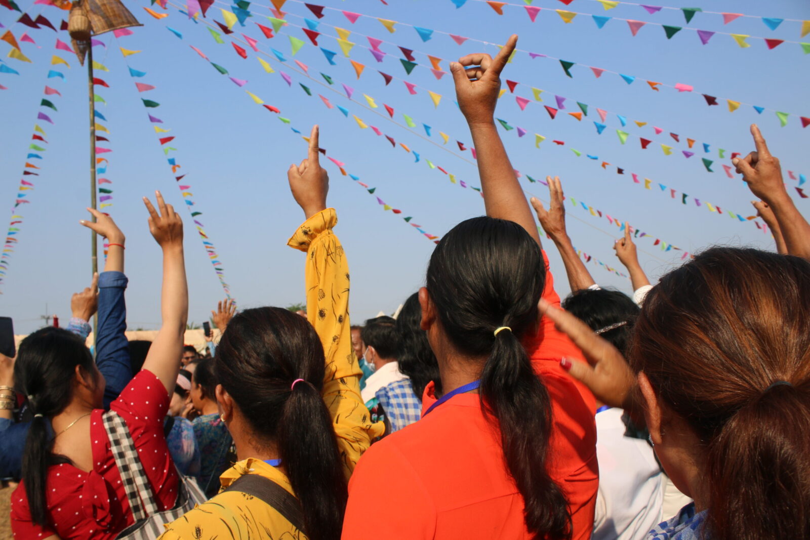 A group of girls standing together with one finger raised.
