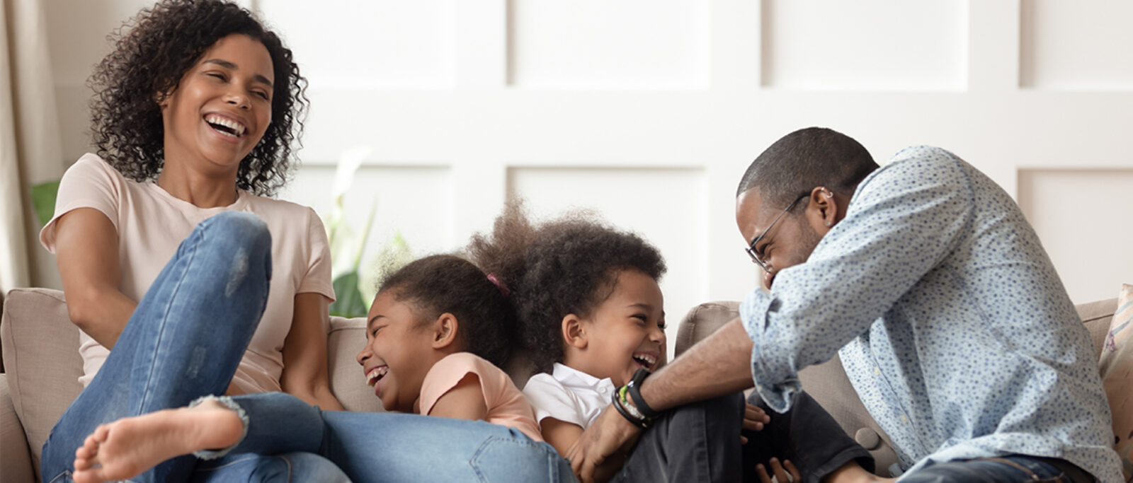 Family laughing on the sofa in their living room